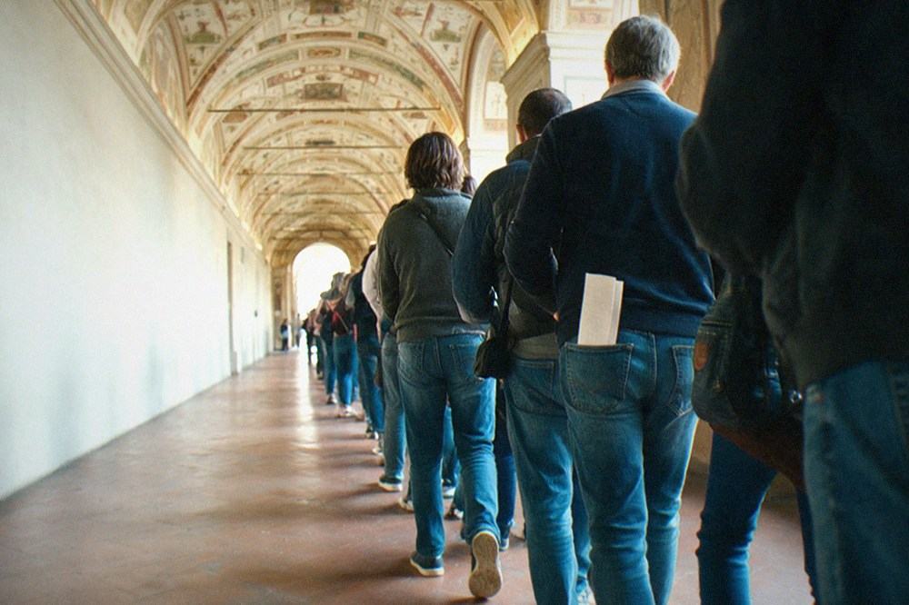 Long gallery with painted ceiling and stone floor stretching toward a bright doorway