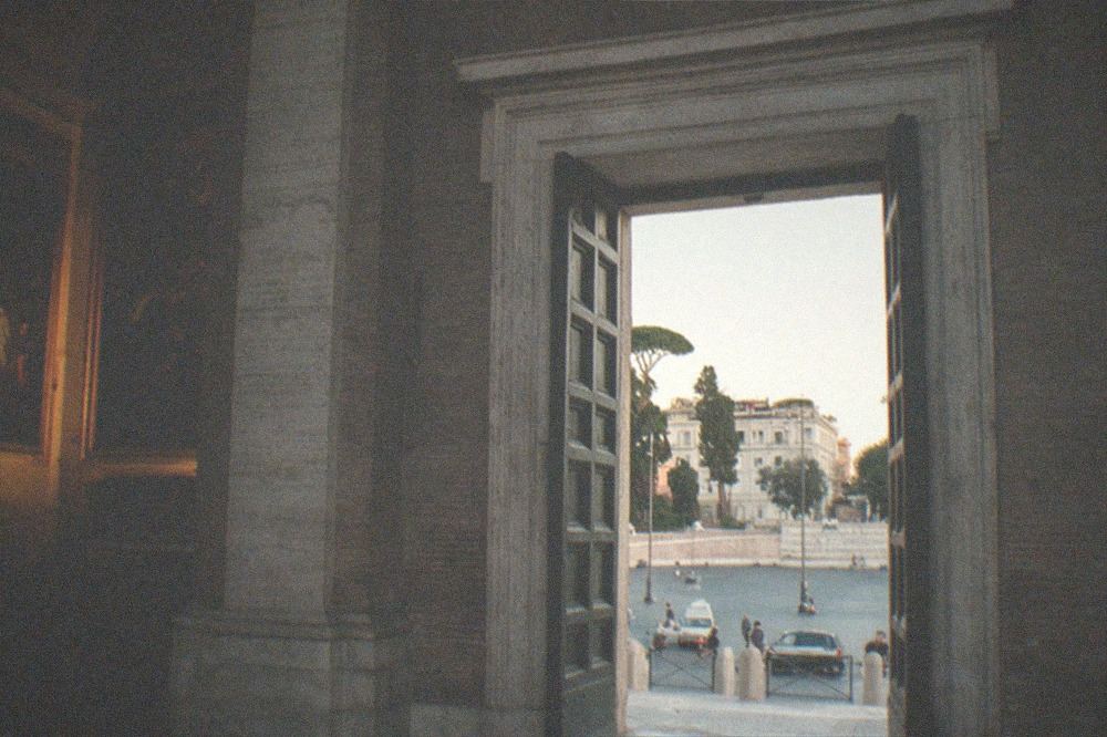 A dim side chapel in a Rome church with two large old-master canvases hung on its side walls