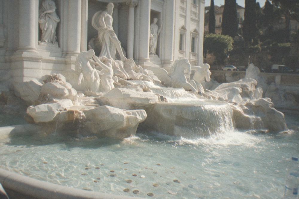 Sunlight hitting the Trevi Fountain's marble facade with water flowing into the basin