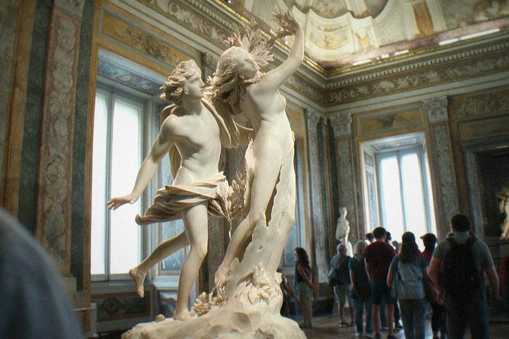 Galleria Borghese interior with Bernini's Apollo and Daphne sculpture in the centre of a frescoed room with gilded details.