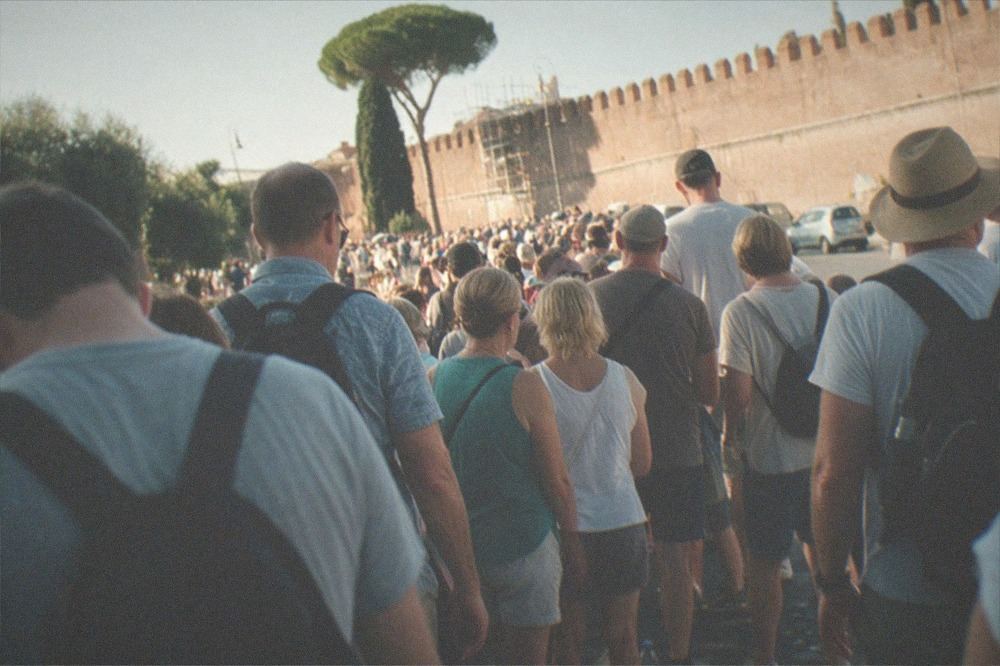 Long queue of visitors waiting outside the Vatican Museums entrance wall