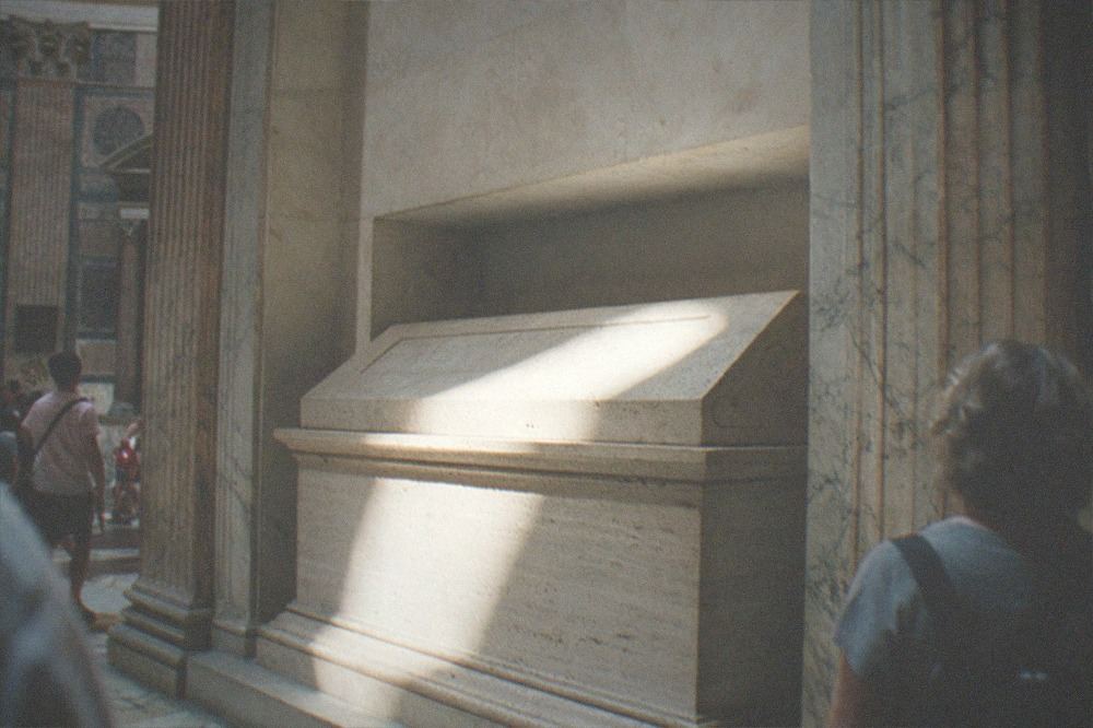 A stone sarcophagus tomb set into a niche inside the round interior of the Pantheon