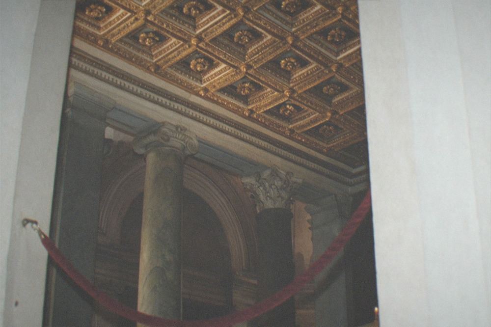 A dim church interior with gilded ceiling and marble columns