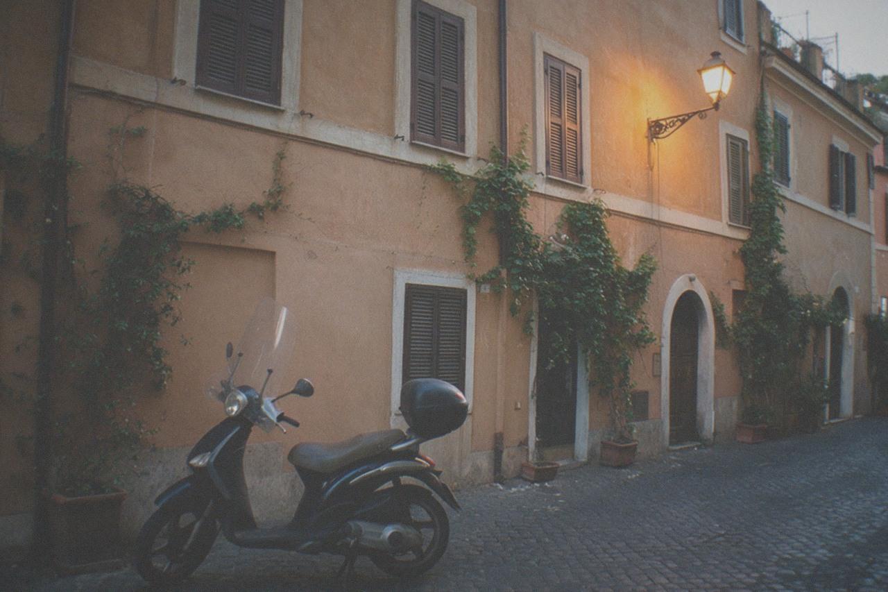 A quiet cobbled Roman street at dusk with ivy-covered ochre walls