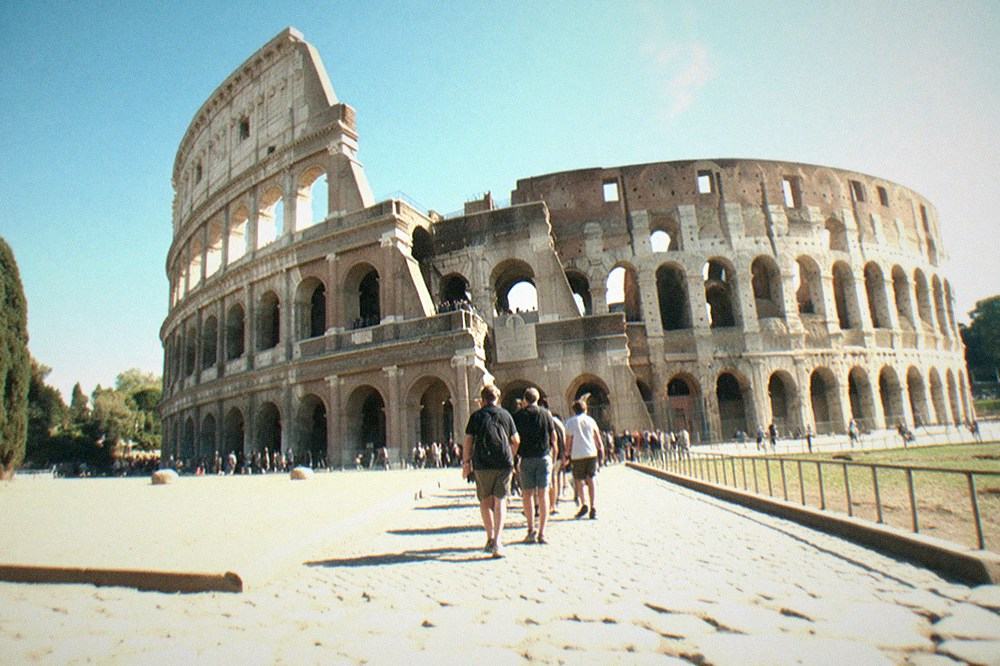 Exterior of the Colosseum under a clear sky seen across a stone plaza