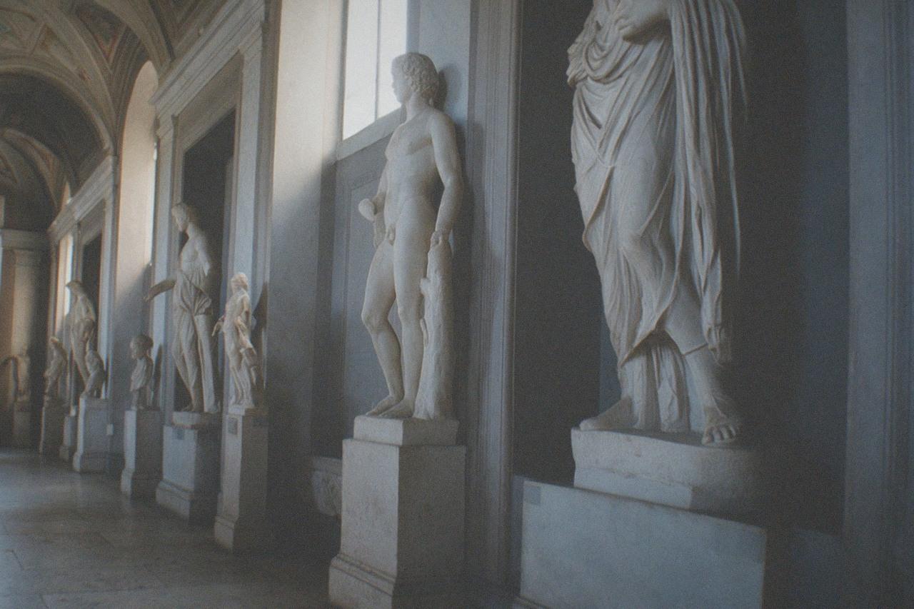 Classical museum gallery with marble statues and painted ceiling under soft daylight