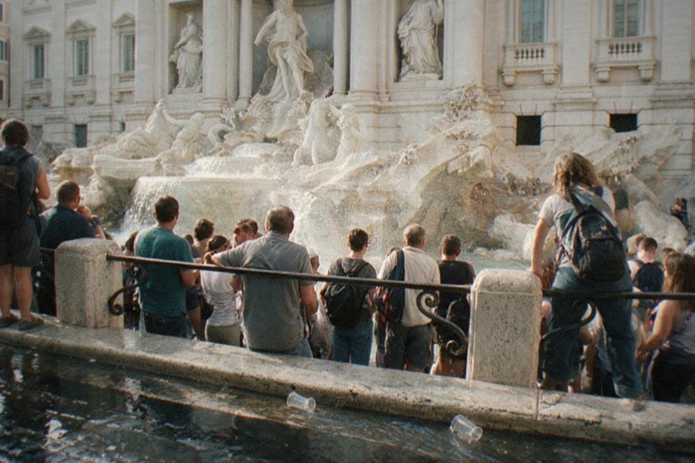 Crowd near a fountain in a busy Roman square at golden hour