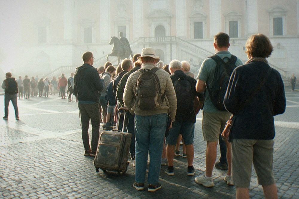 Museum entrance with columns and a queue of visitors in morning light