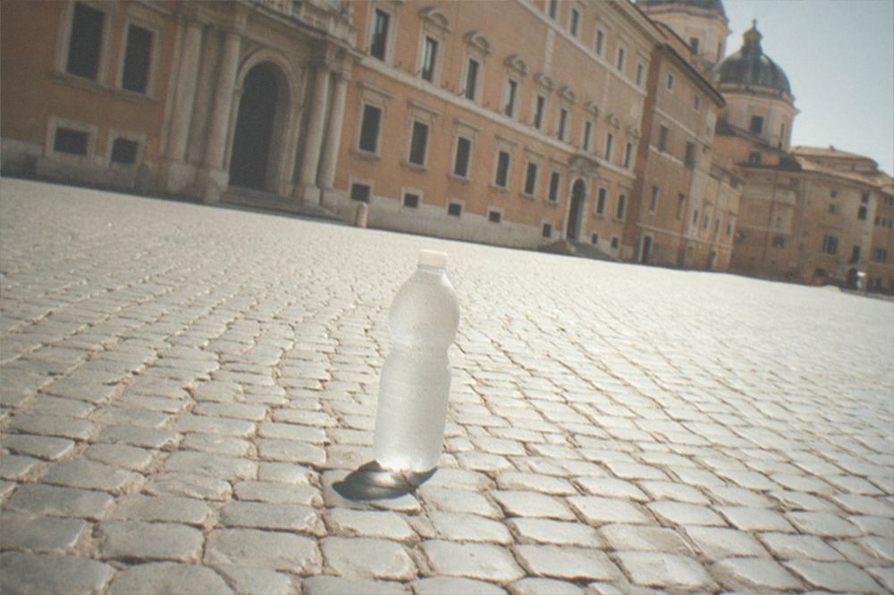 A guide speaking to a small standing group in a sunlit Roman piazza