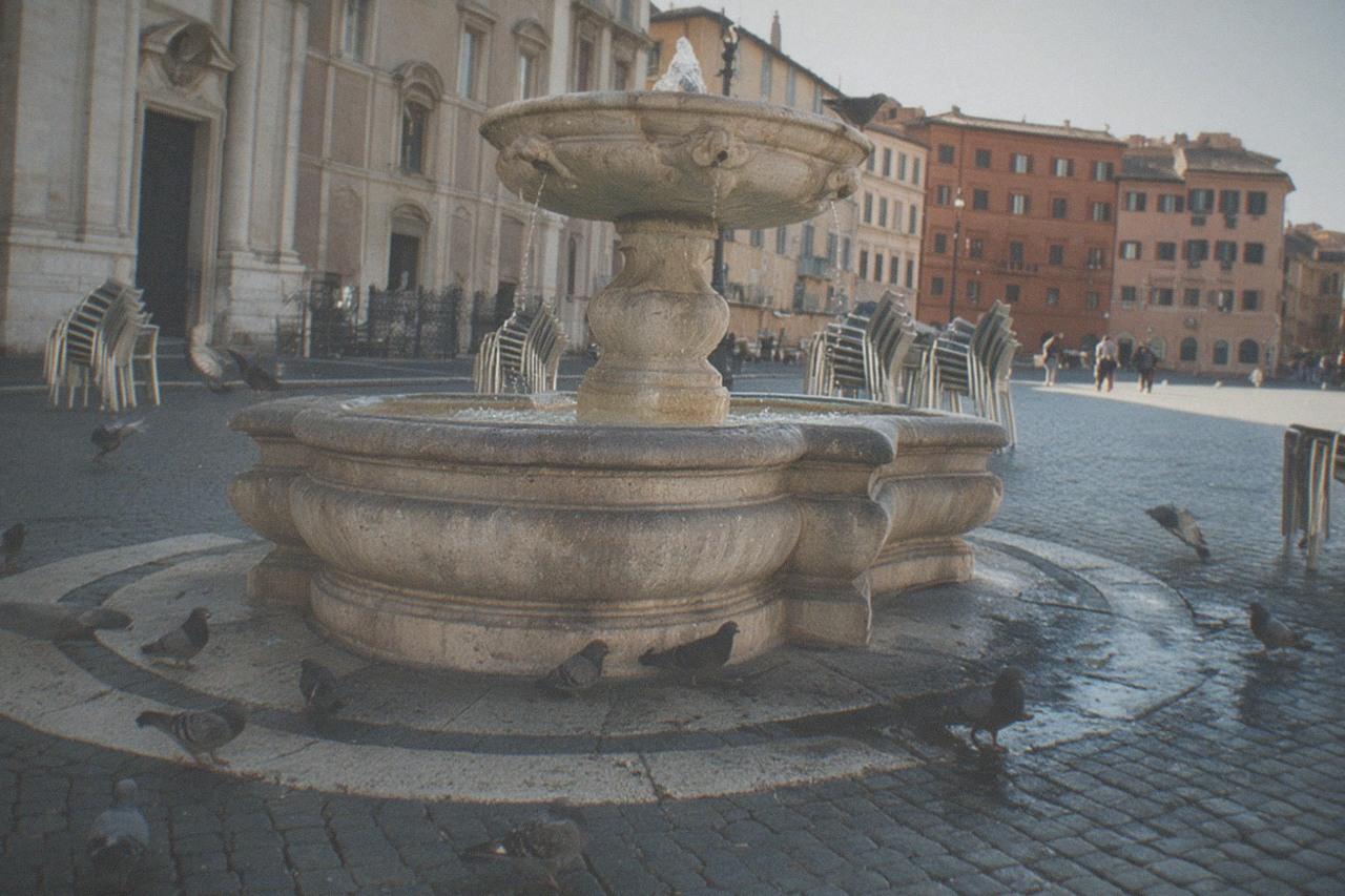 A quiet Rome piazza in morning light with stone facades and an old fountain