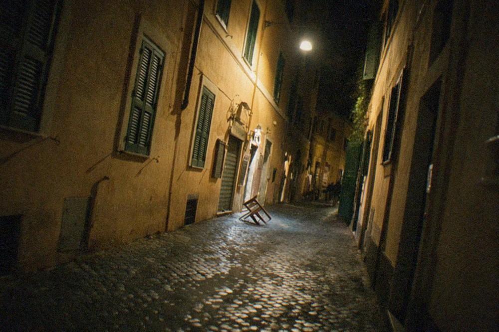 Illuminated Roman alley at night with closed shutters and a single street lamp