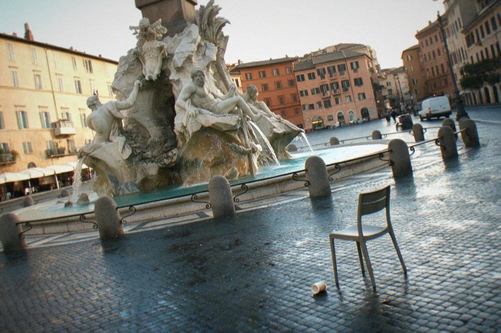 A wide Roman piazza with fountains, ochre facades and soft evening light on the buildings