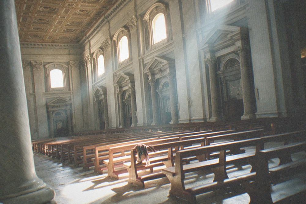 A baroque church interior with gilded ceiling decoration, marble columns and side chapels