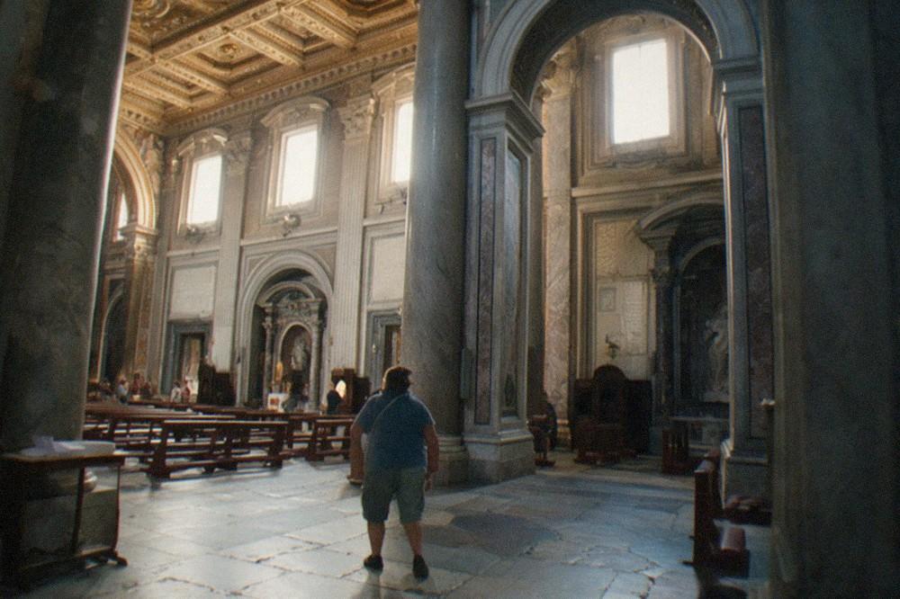 Sunlit baroque church interior with marble columns, gilded ceiling and stone floor