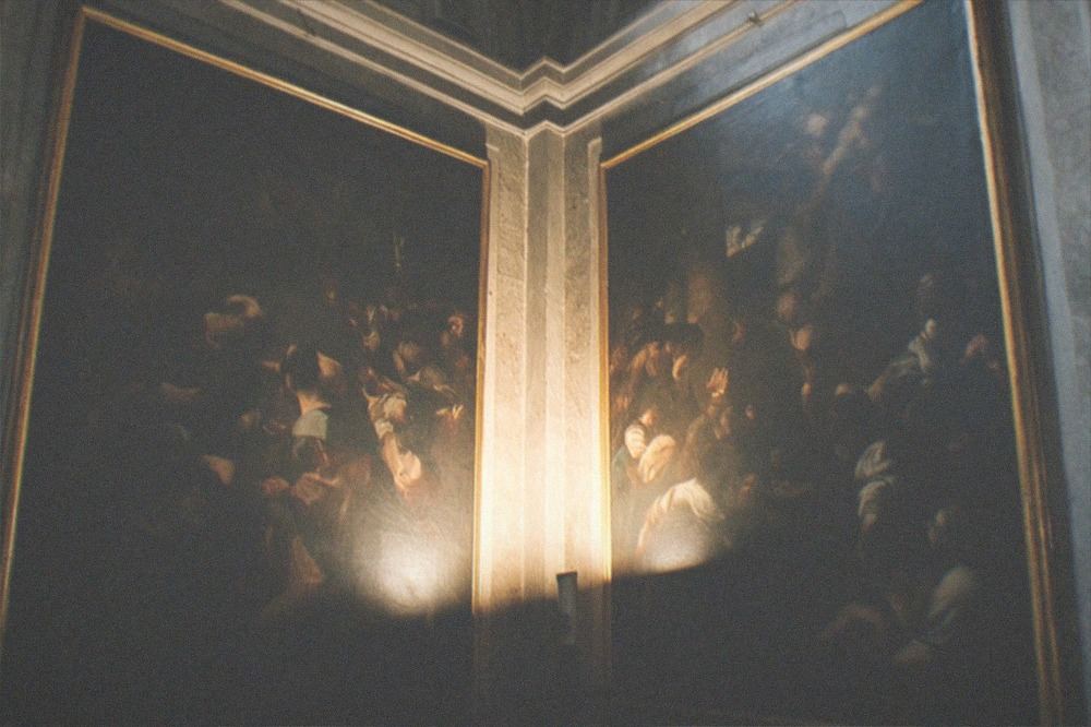Paintings lit inside a dark side chapel of an old Roman church