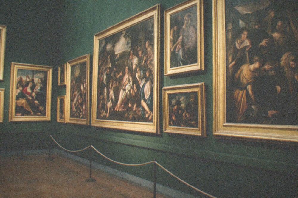 Renaissance painting gallery with gilded frames hung in rows on a dark wall