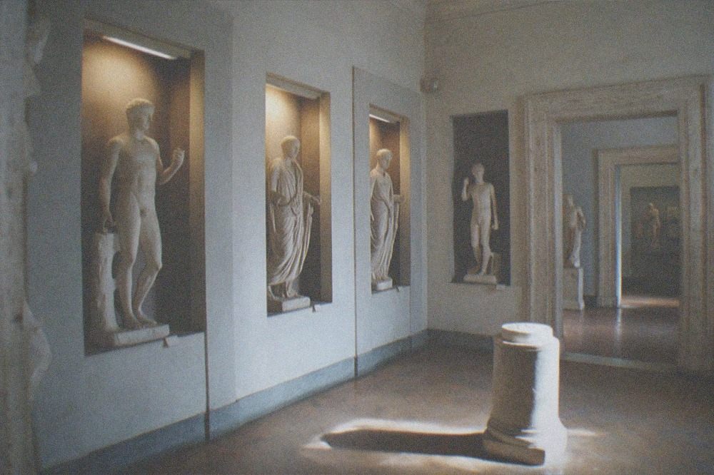 Museum interior with classical statues in niches and warm lamplight