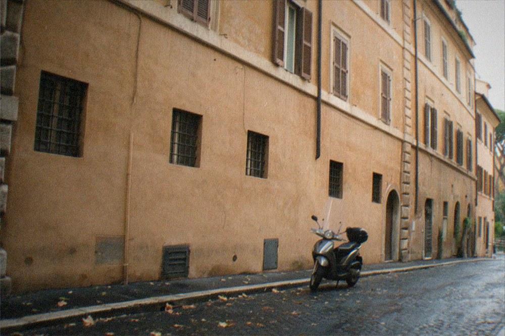 Old stone building facade with small barred windows on a quiet Rome street