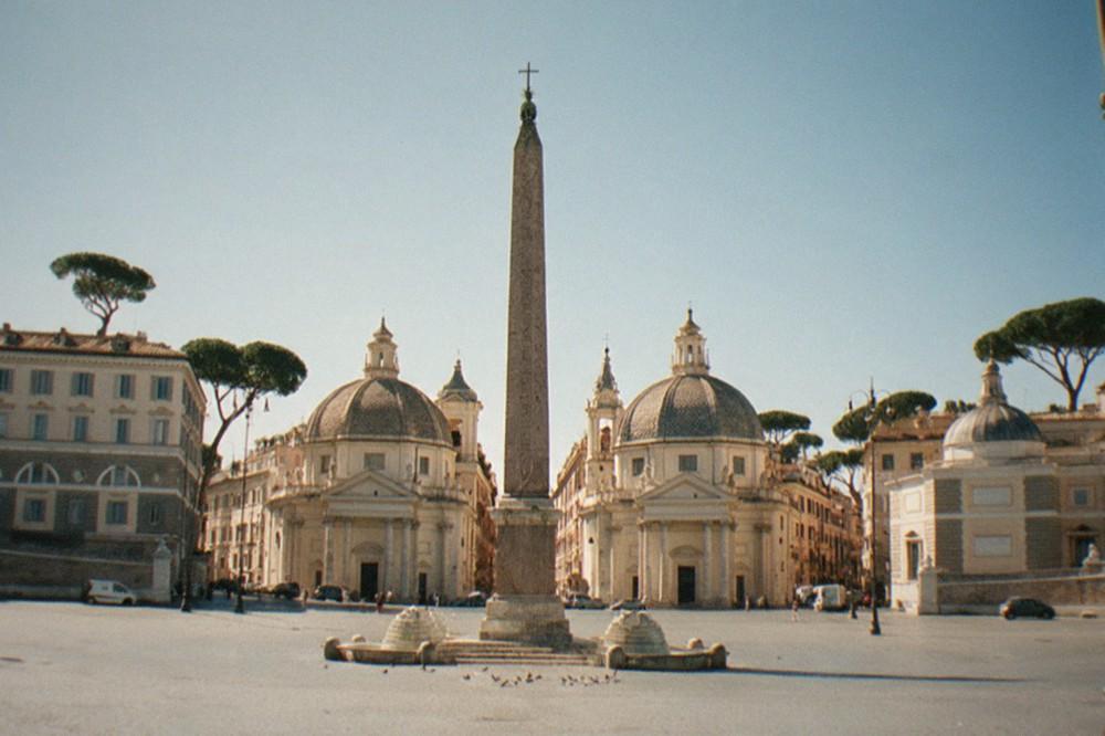 A quiet Roman piazza with church domes under a clear sky