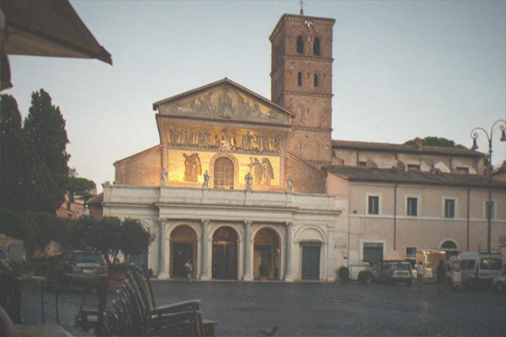 Façade of a Trastevere basilica with a bell tower in evening light