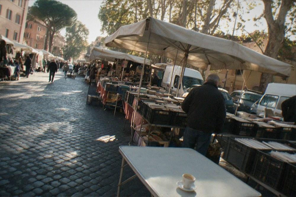 Rows of market stalls along a wide Roman street in morning light