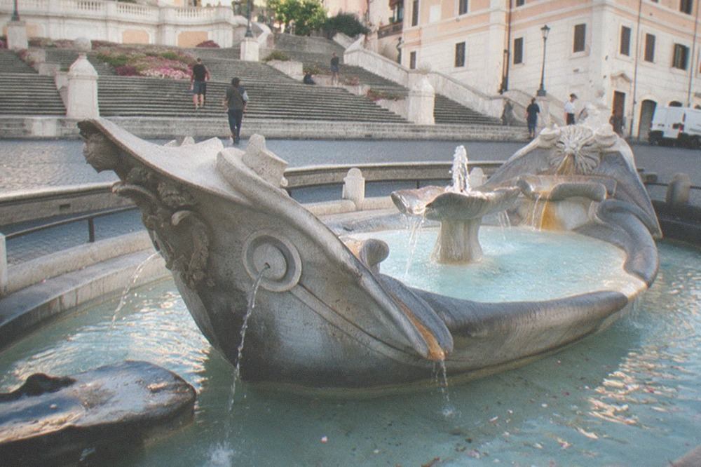 A baroque fountain with sculpted figures in a Roman square at golden light
