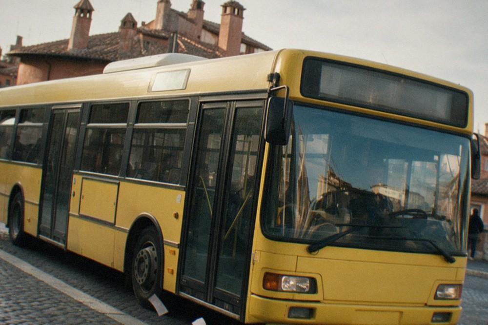 A Rome bus stopped at a cobblestoned curb with the city's terracotta rooftops rising behind it.