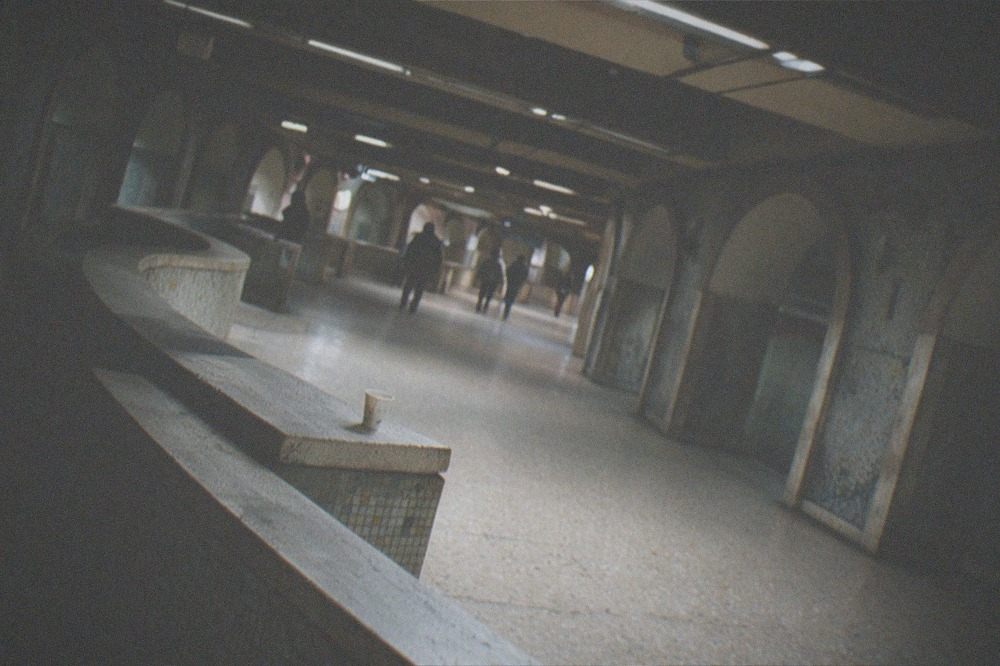 Rome metro train approaching a platform inside a station with mosaics and low-lit arches.