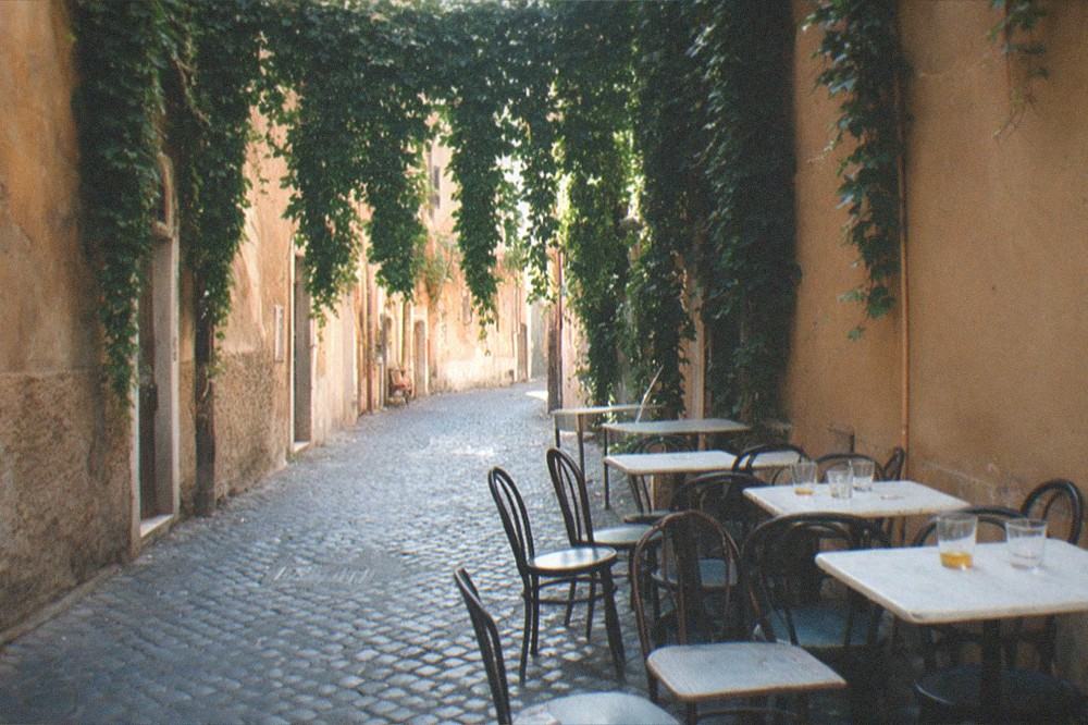 A cobbled lane in Trastevere with hanging ivy and a small trattoria terrace.