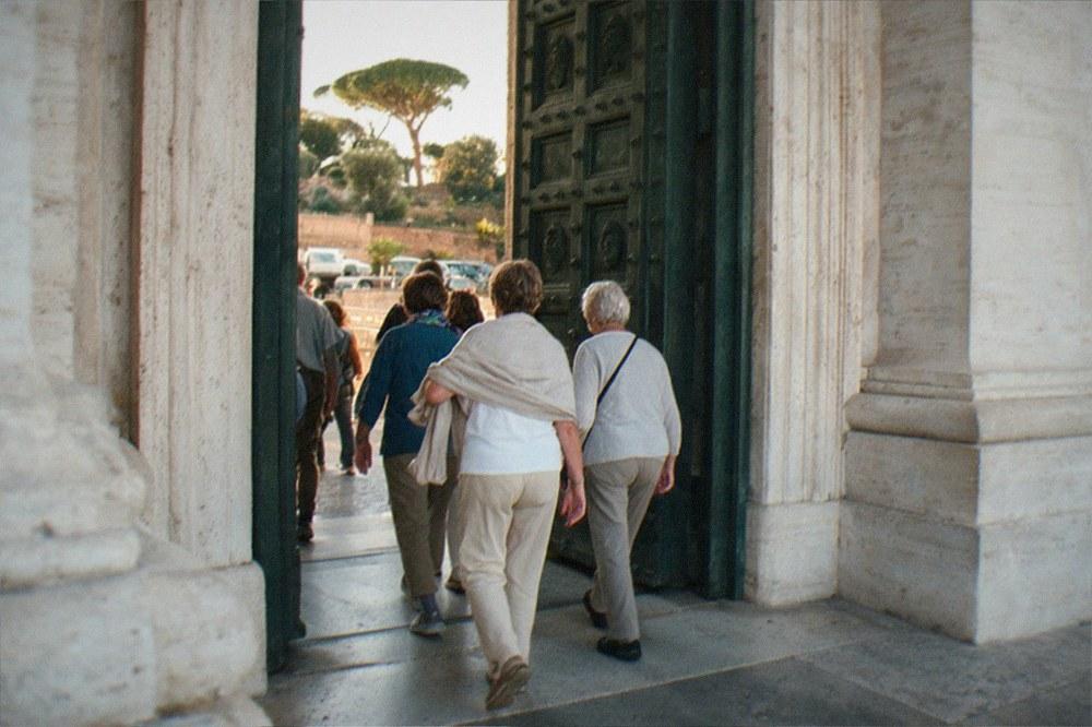 Visitors in modest clothing walking through a church entrance in Rome
