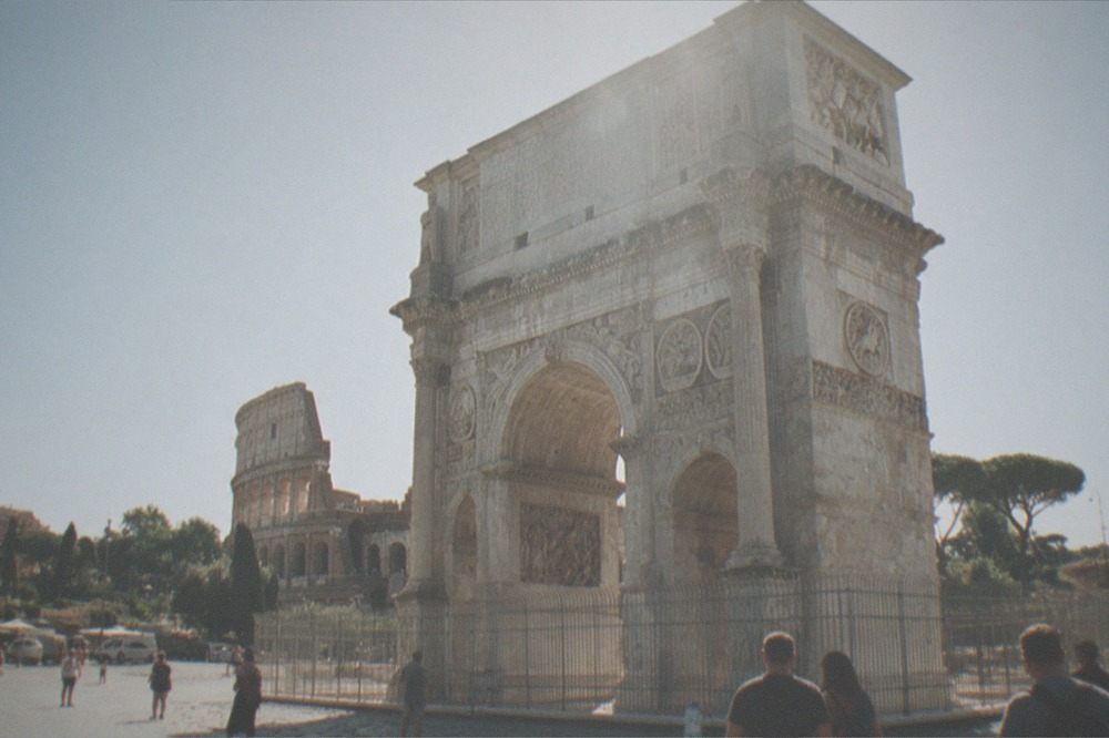 The Arch of Constantine standing in an open paved square near the Colosseum