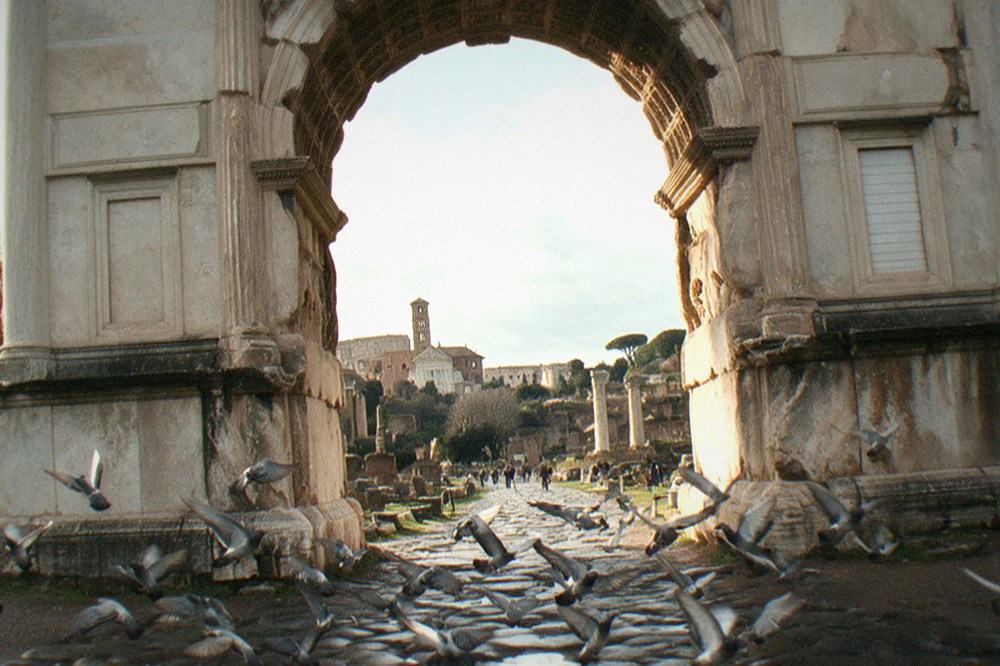 Stone archway of the Arch of Titus framing ancient ruins along the Via Sacra