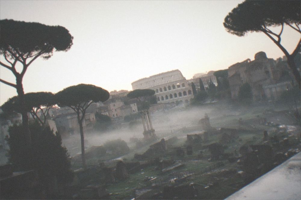 Wide view over the Roman Forum valley with the Colosseum visible in the distance