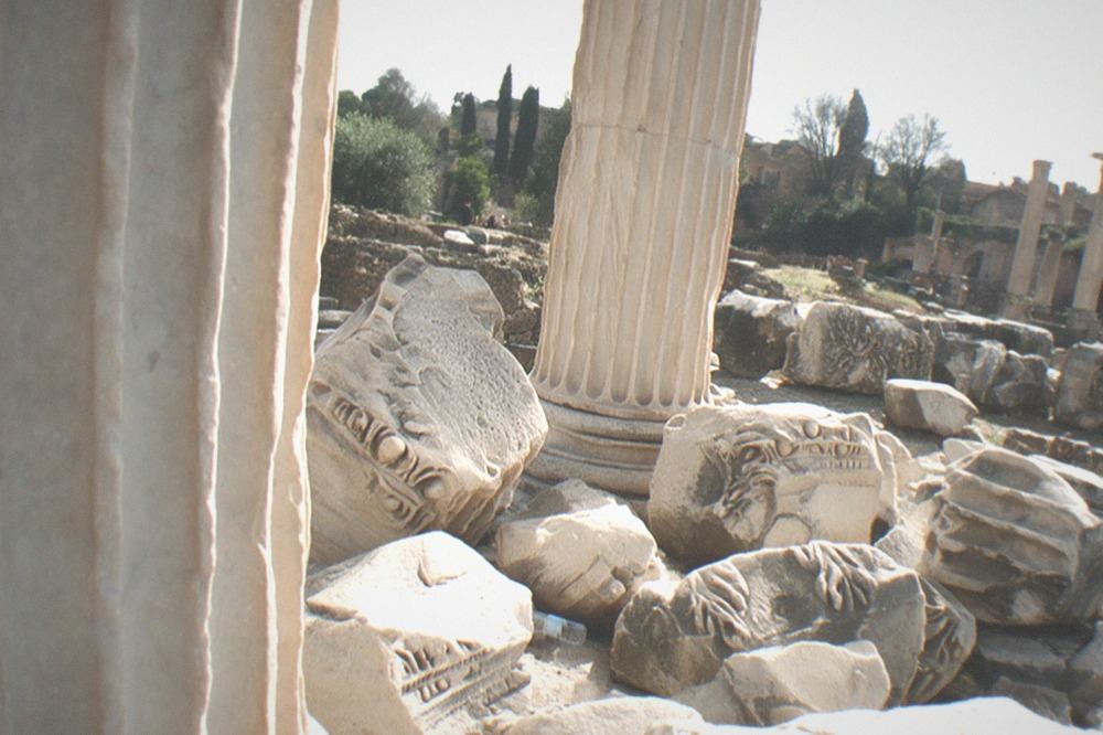 Close view of carved marble fragments and a standing column in the Forum excavations