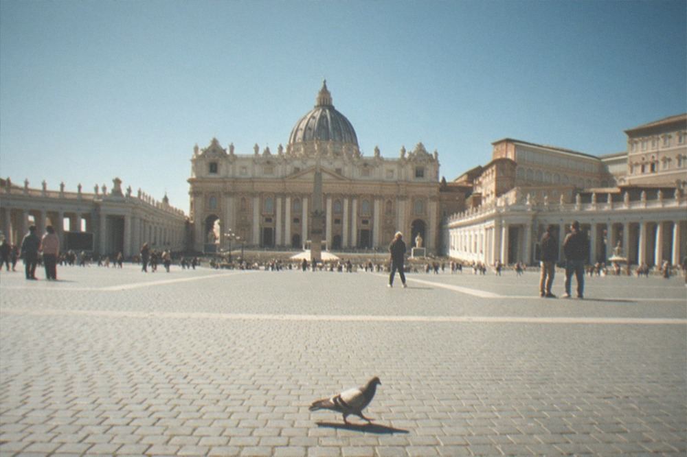 St Peter's Square seen from a distance, with the basilica facade and colonnades under a clear sky