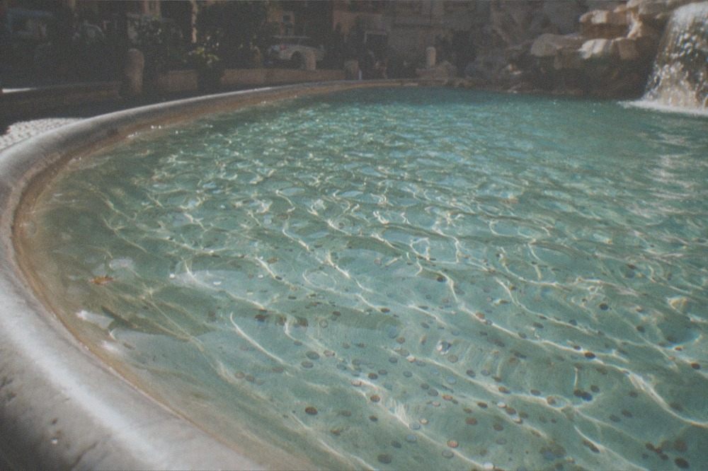 Clear water in the Trevi Fountain basin with coins visible on the bottom
