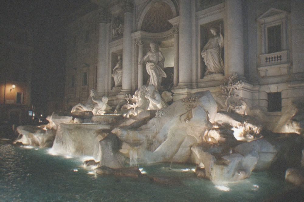 The Trevi Fountain lit at night with baroque sculptures and flowing water
